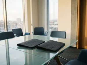 Zwei Dokumentenmappen auf einem Glastisch in einem modernen Erfurter Büro mit Stadtpanorama im Hintergrund.
